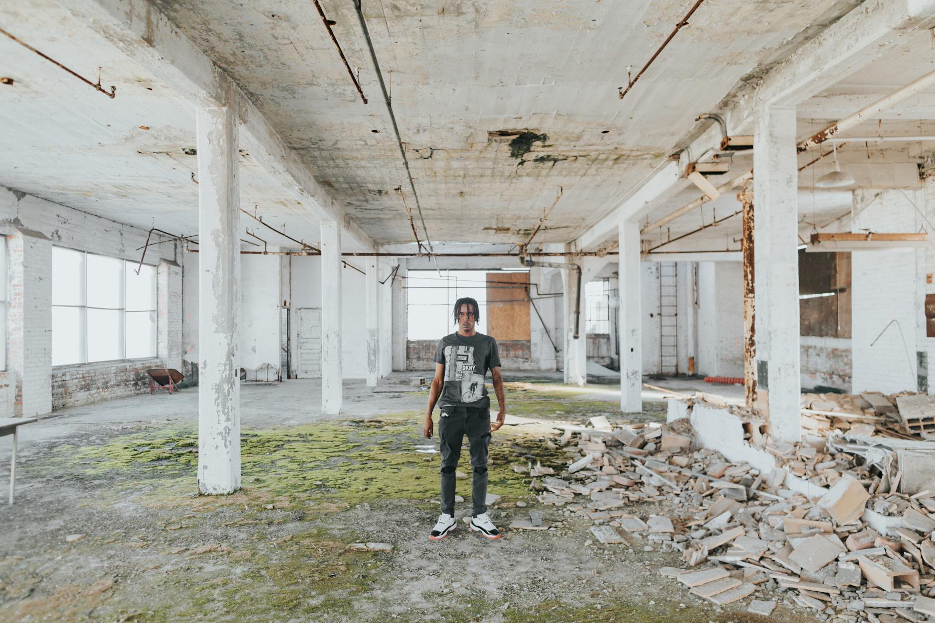 Explore the raw, gritty atmosphere of an abandoned building in Detroit with a solitary man amidst debris.