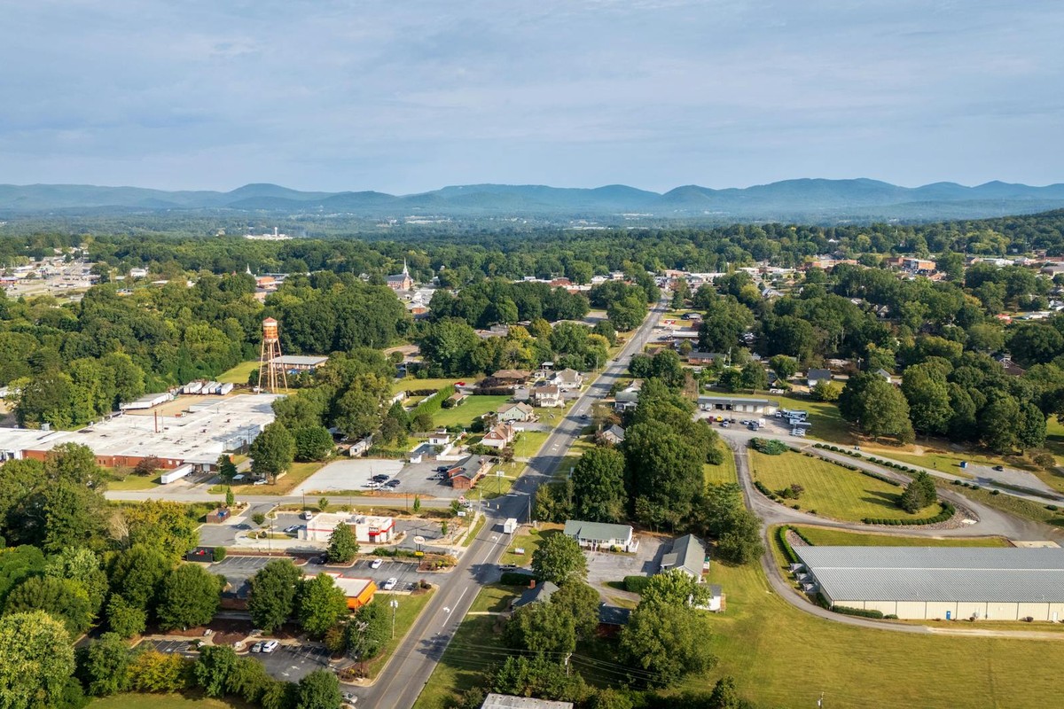 Aerial scenery of a town with lush greenery and distant mountains under clear skies.