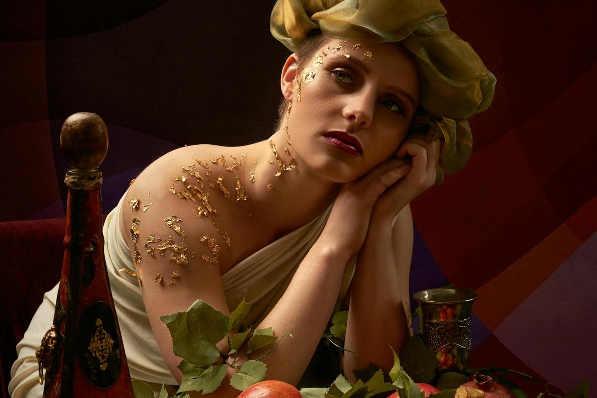 A woman in a classical pose with fruit and leaves, evoking an artistic, vintage style.
