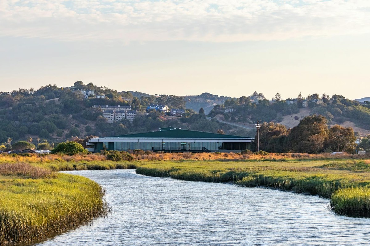 Scenic landscape of a river flowing through a rural area with hills in the background.