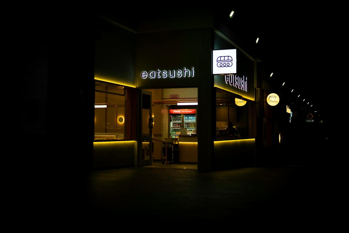 Night view of a warmly illuminated sushi restaurant entrance in Springfield, QLD, Australia.