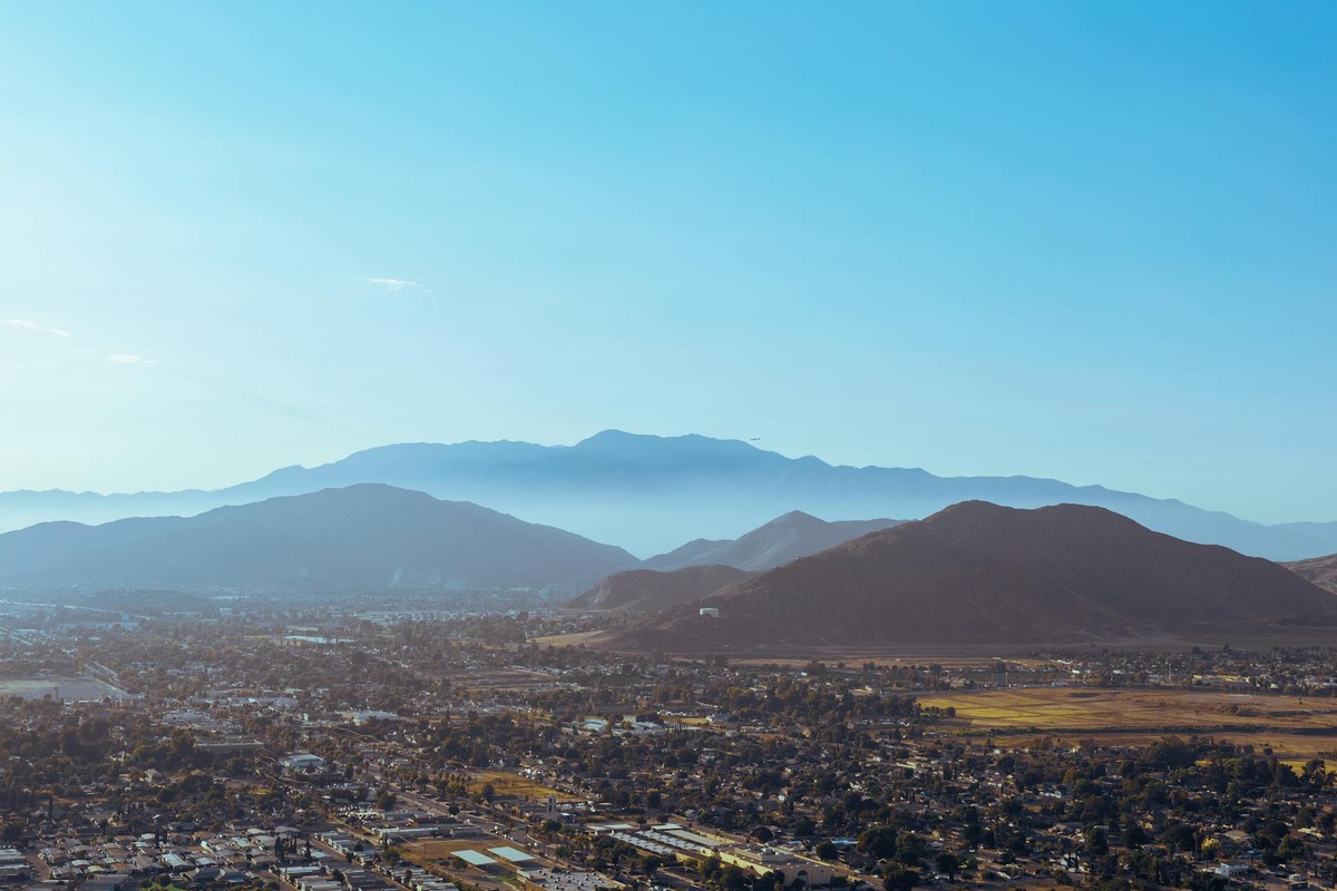 A stunning aerial view of mountains embracing the city under a blue sky.