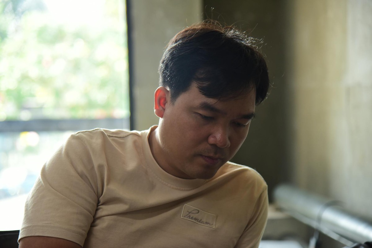 Asian man in thoughtful moment indoors, captured in natural light with soft focus.