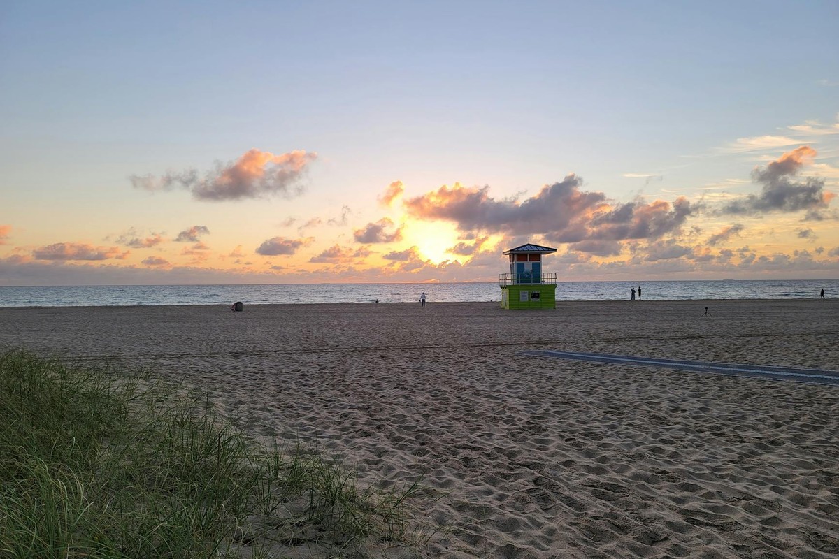 A tranquil sunrise over Fort Lauderdale Beach with a vibrant lifeguard tower and golden sands.