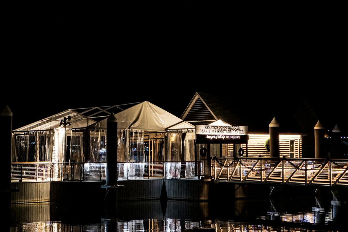 A beautifully lit maritime center at night, reflecting on calm water.