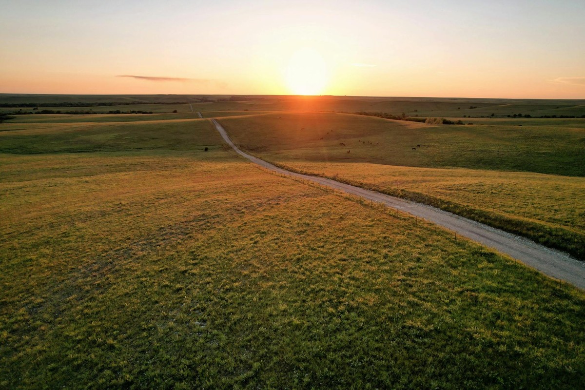 A serene sunset over rural fields with a winding dirt road in Eureka, Kansas.