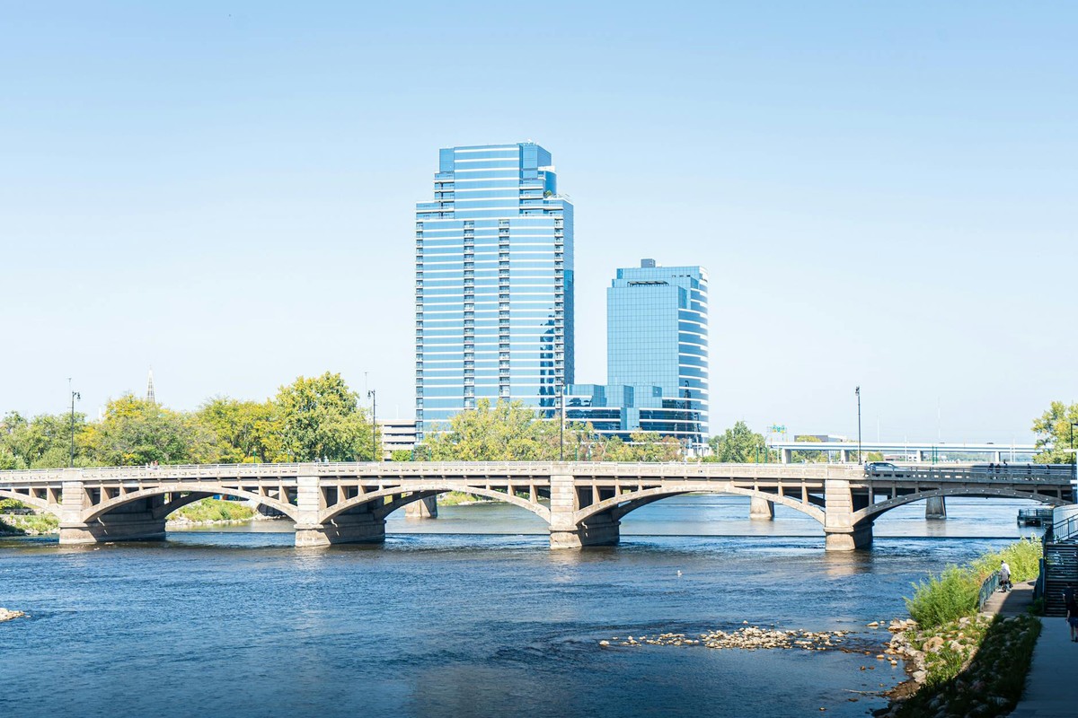 Scenic view of downtown Grand Rapids with iconic bridge and modern skyscrapers reflecting on the river.