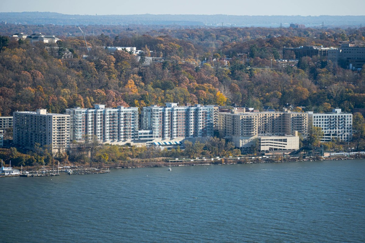 Aerial shot of riverside apartments surrounded by autumn foliage.