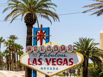 The classic 'Welcome to Las Vegas' sign amidst palm trees, under a bright blue sky.