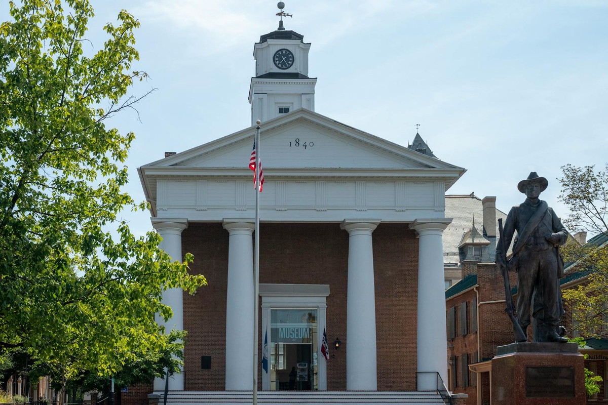 Historic courthouse facade with statue and American flag in daylight.