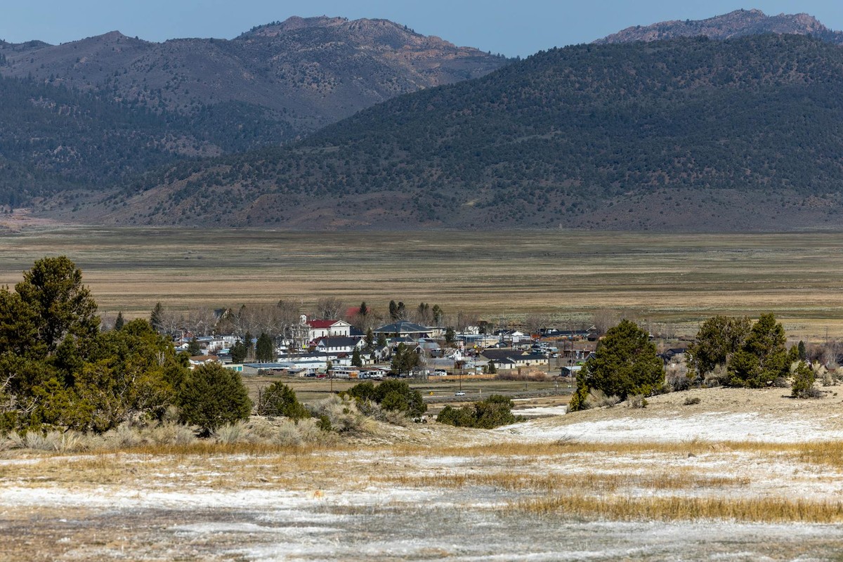 A scenic view of a small town nestled in a mountain valley with clear skies and rolling hills.