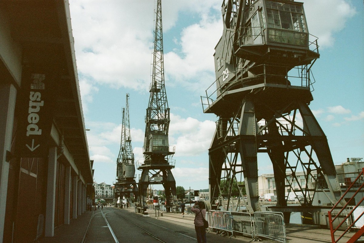 View of historic cranes and M Shed at Bristol Harborside on a sunny day.