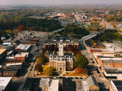 Drone view of aged stone building facades near urban roadways and bright trees in town in fall