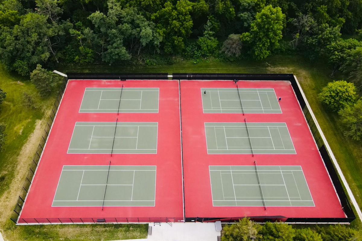 Aerial perspective of multiple tennis courts surrounded by lush greenery in West Des Moines.