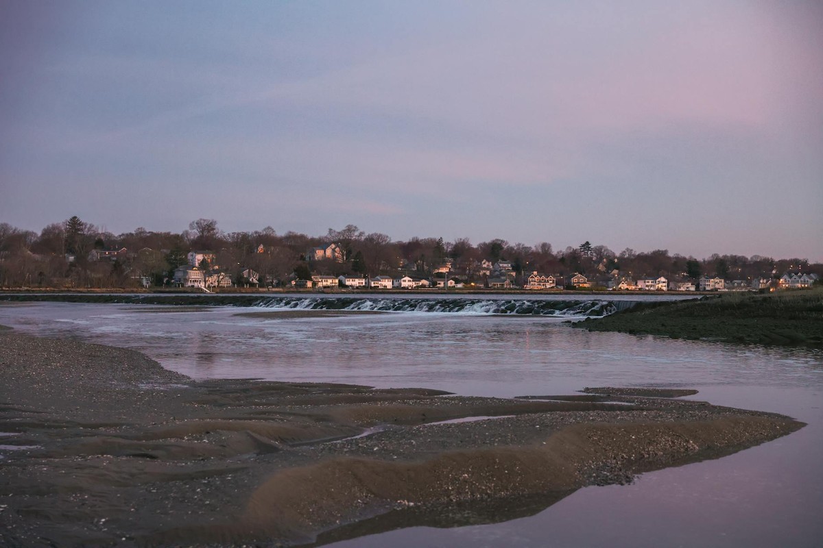 Scenic view of Stamford, CT houses reflecting on river at twilight.