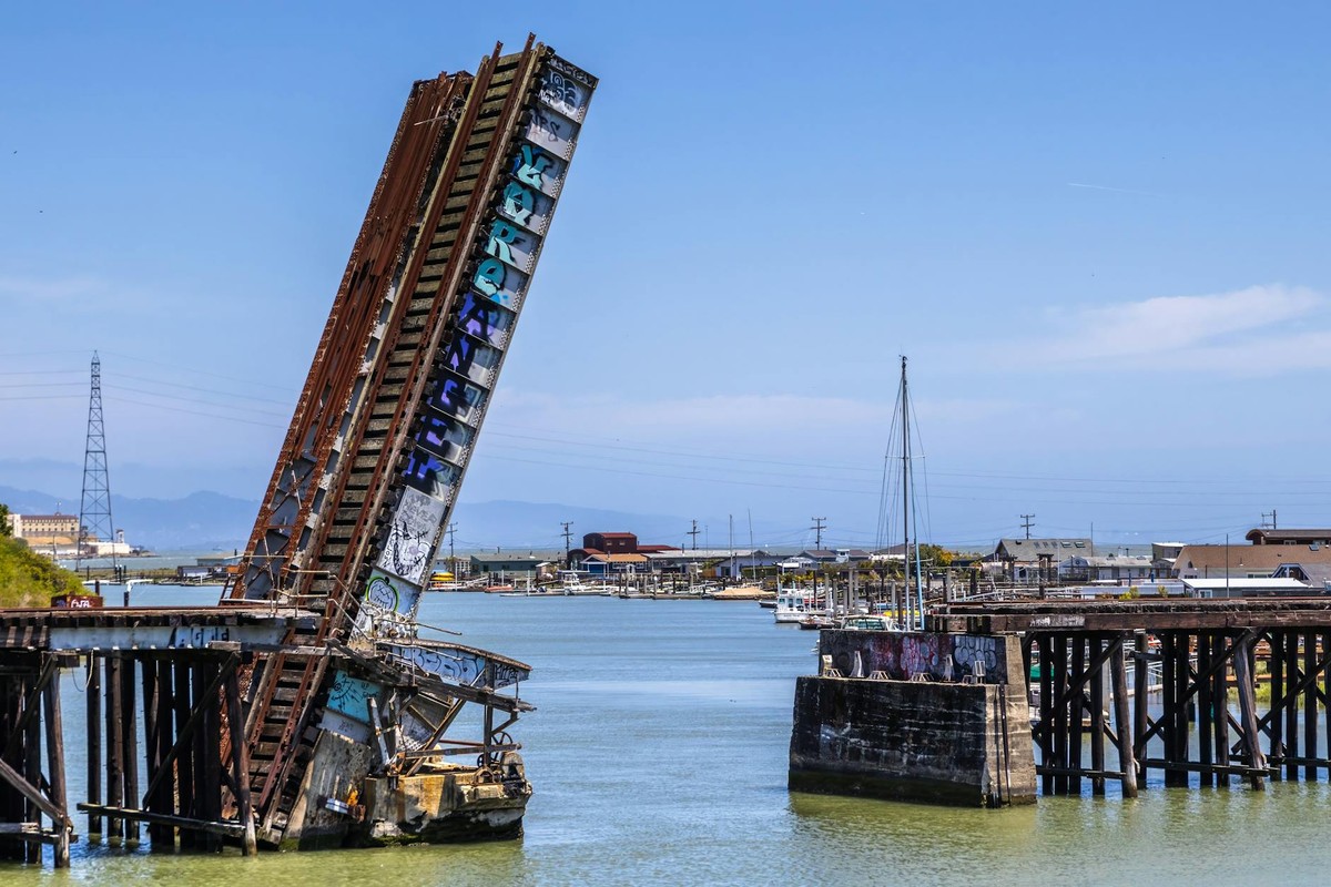 Aged railroad drawbridge over Corte Madera Creek in Marin County, California with graffiti on structure.