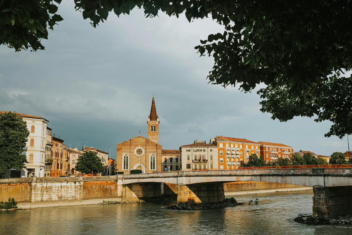 Beautiful view of a historic bridge over the river in Verona, Italy, under a cloudy sky.