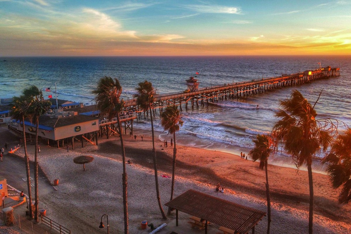 A breathtaking sunset view from above of a scenic beach with a long pier extending into the ocean.