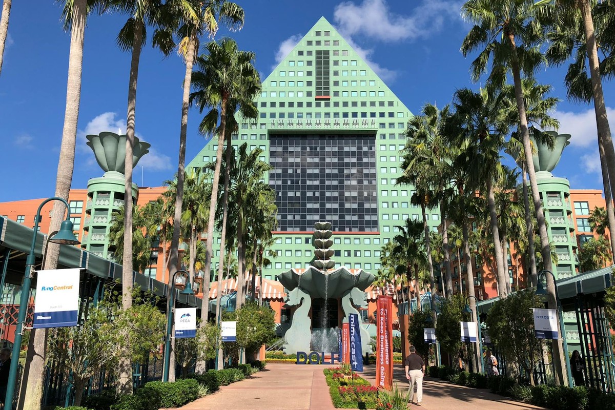 Iconic Swan Hotel at Walt Disney World in Kissimmee, FL with lush palm trees and clear skies.