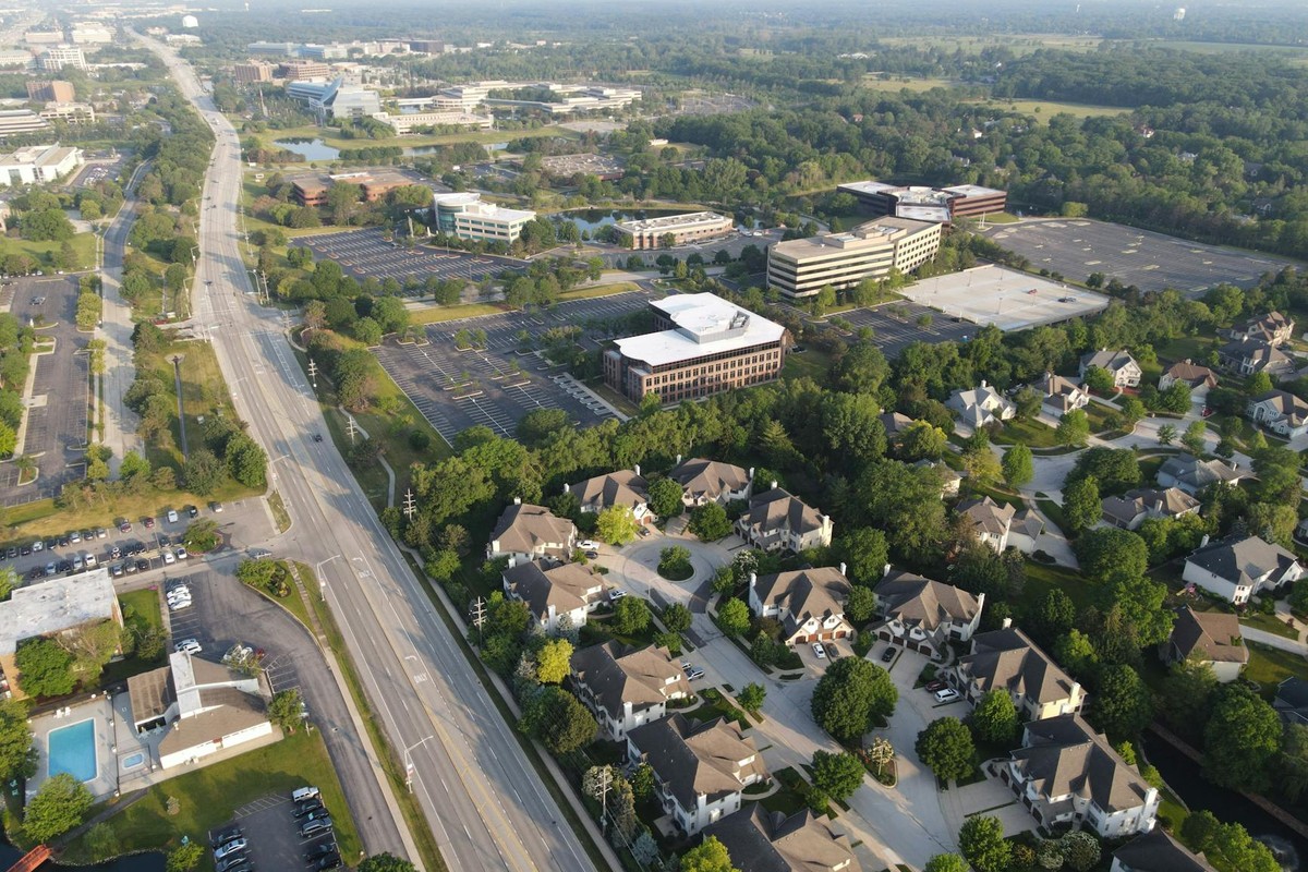 Aerial photo showcasing suburban Lisle, IL with roads, trees, and buildings under clear skies.