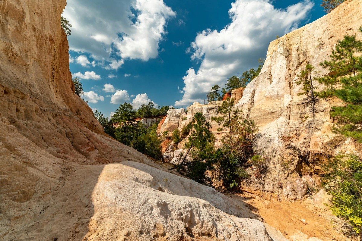 Vibrant sandstone formations at Providence Canyon State Park, Georgia, under bright blue skies.
