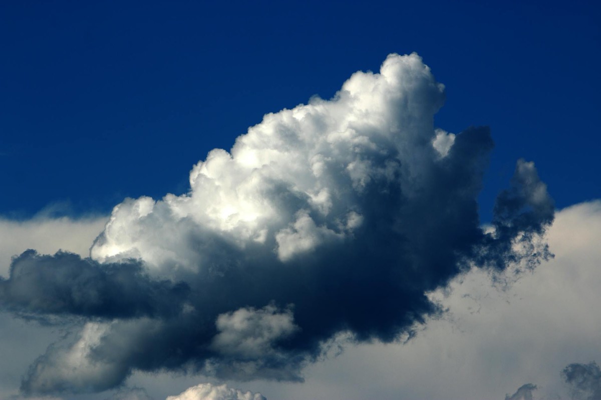 A striking cumulus cloud against a vivid blue sky, showcasing dynamic weather patterns.