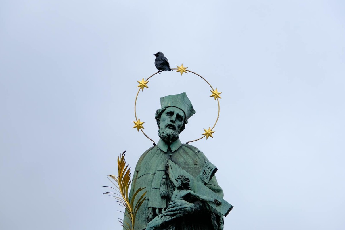 Statue of St. John of Nepomuk with a crow atop, located in Prague, Czech Republic.