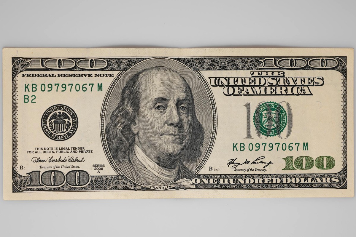 A detailed close-up of a US $100 bill featuring Benjamin Franklin on a white background.