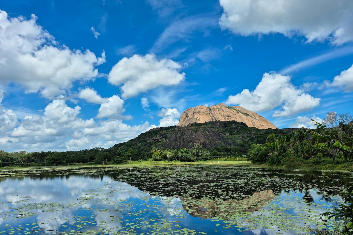 Breathtaking view of Savandurga Hill in Karnataka reflecting in a serene lake.