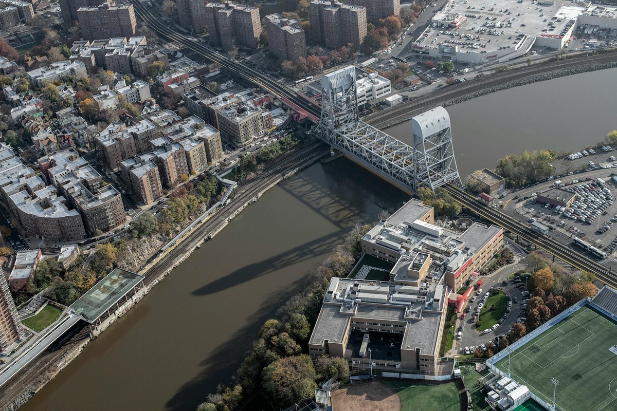 Aerial shot of New York City's urban landscape featuring a bridge over a river and residential buildings.