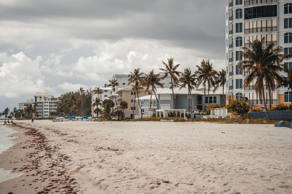Beautiful resort on a sandy beach with palm trees under a cloudy sky, perfect for a summer vacation.