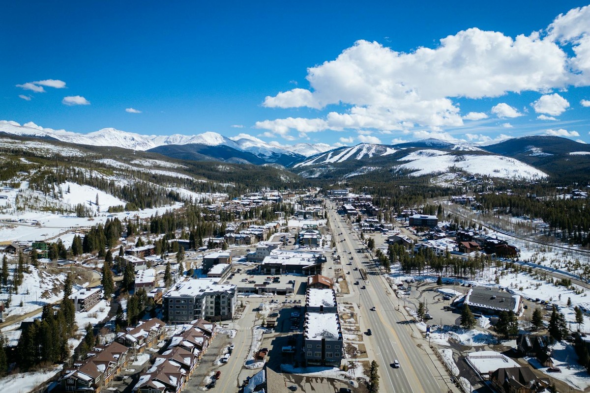 Aerial photo of a snow-covered town with distant mountains, taken in daylight.
