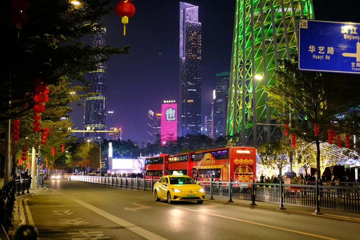 Colorful urban nightscape in Guangzhou with skyscrapers, a yellow taxi, and festive lanterns.