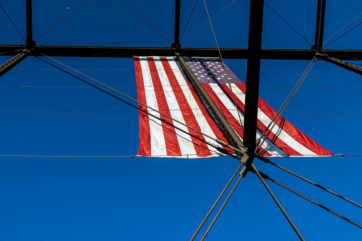American flag displayed on Folsom's historic truss bridge against a clear sky.