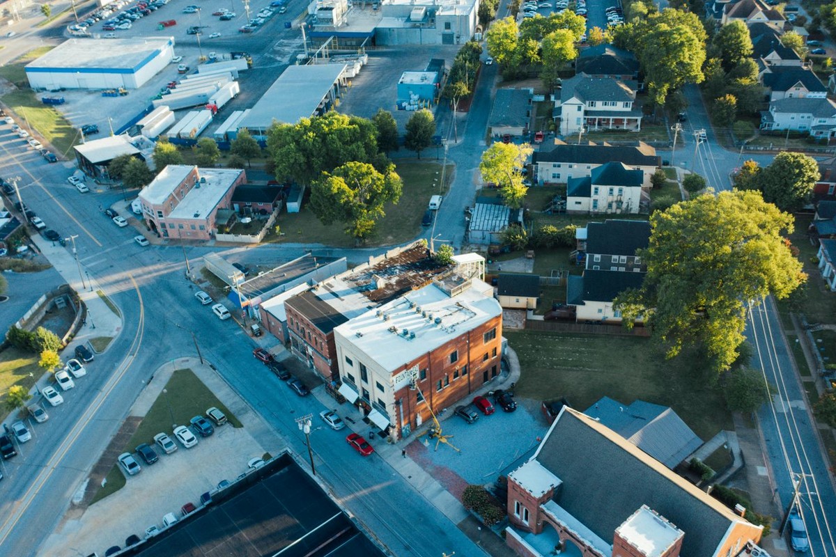 Drone view of typical small buildings located near asphalt roads in suburban district on sunny day