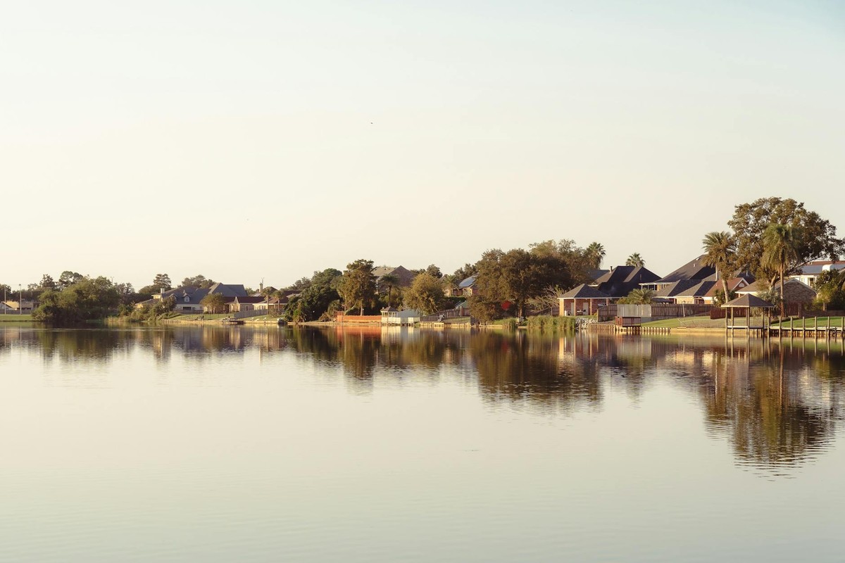 Peaceful lakefront view in New Orleans, Louisiana, showcasing waterside houses with vibrant reflections.