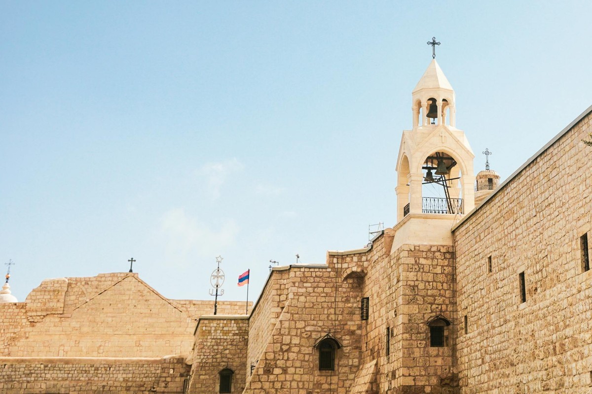 Stone facade of a historical church in Bethlehem under a clear blue sky.