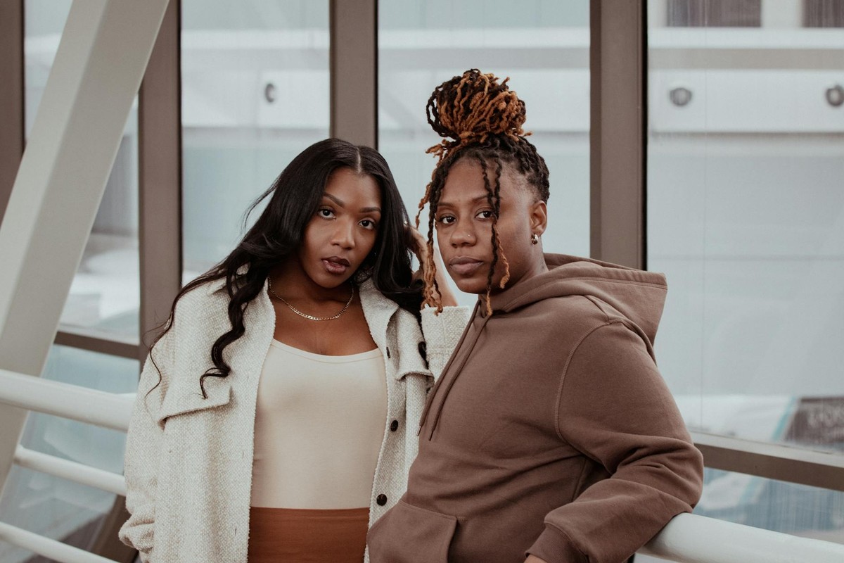 A fashionable couple standing together in an urban indoor setting, exuding confidence and style.