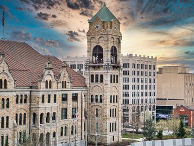 A classic shot of a historic bell tower against a dramatic sunset sky in an urban setting.