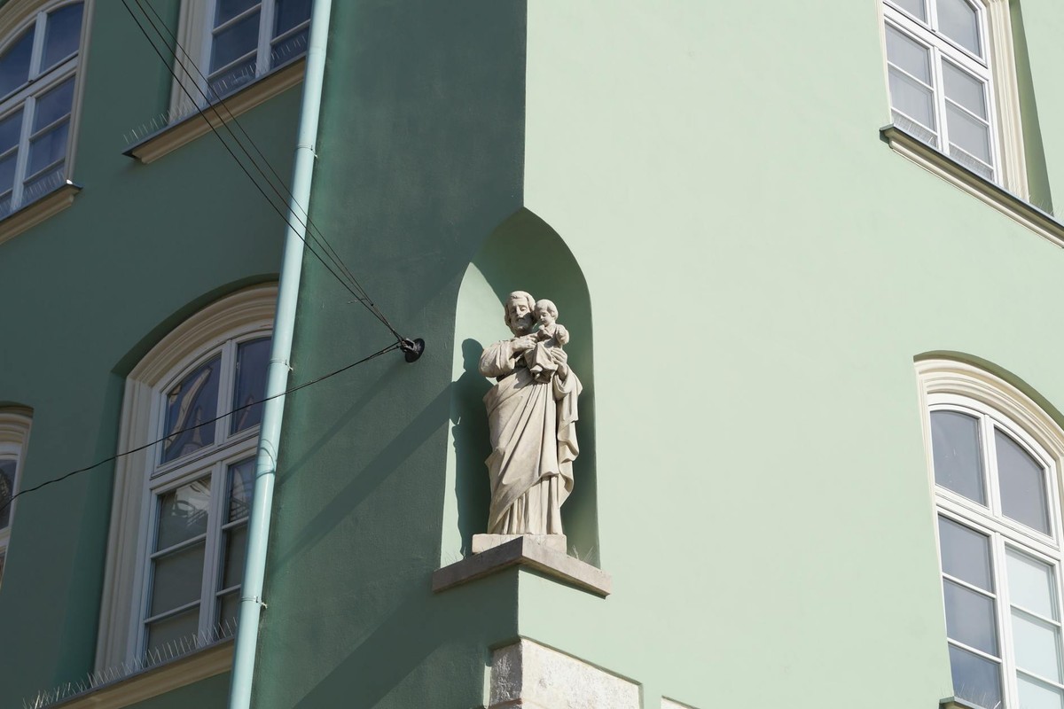 A religious statue on a Kraków building showcasing Renaissance architecture.