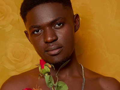 A thoughtful portrait of a man holding red roses against a yellow floral backdrop.