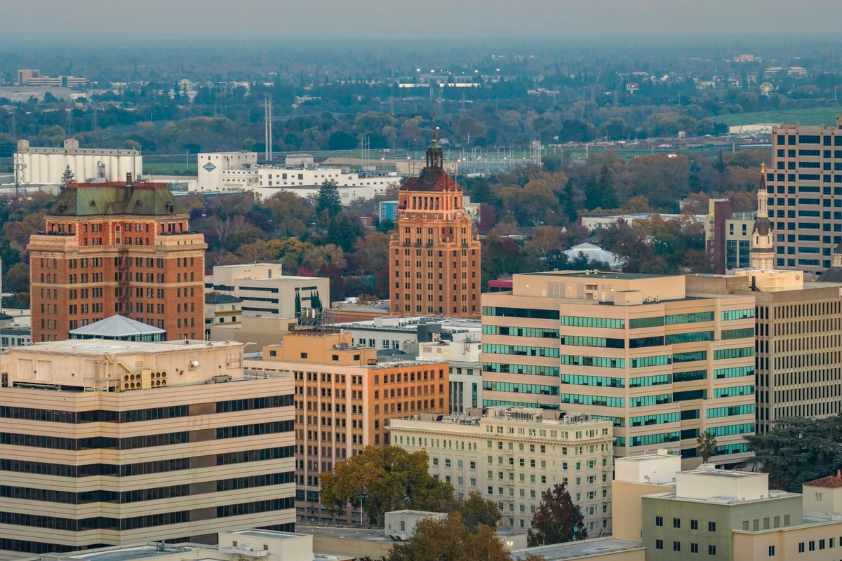 Aerial shot of downtown Sacramento, showcasing iconic buildings and autumn foliage at sunset.