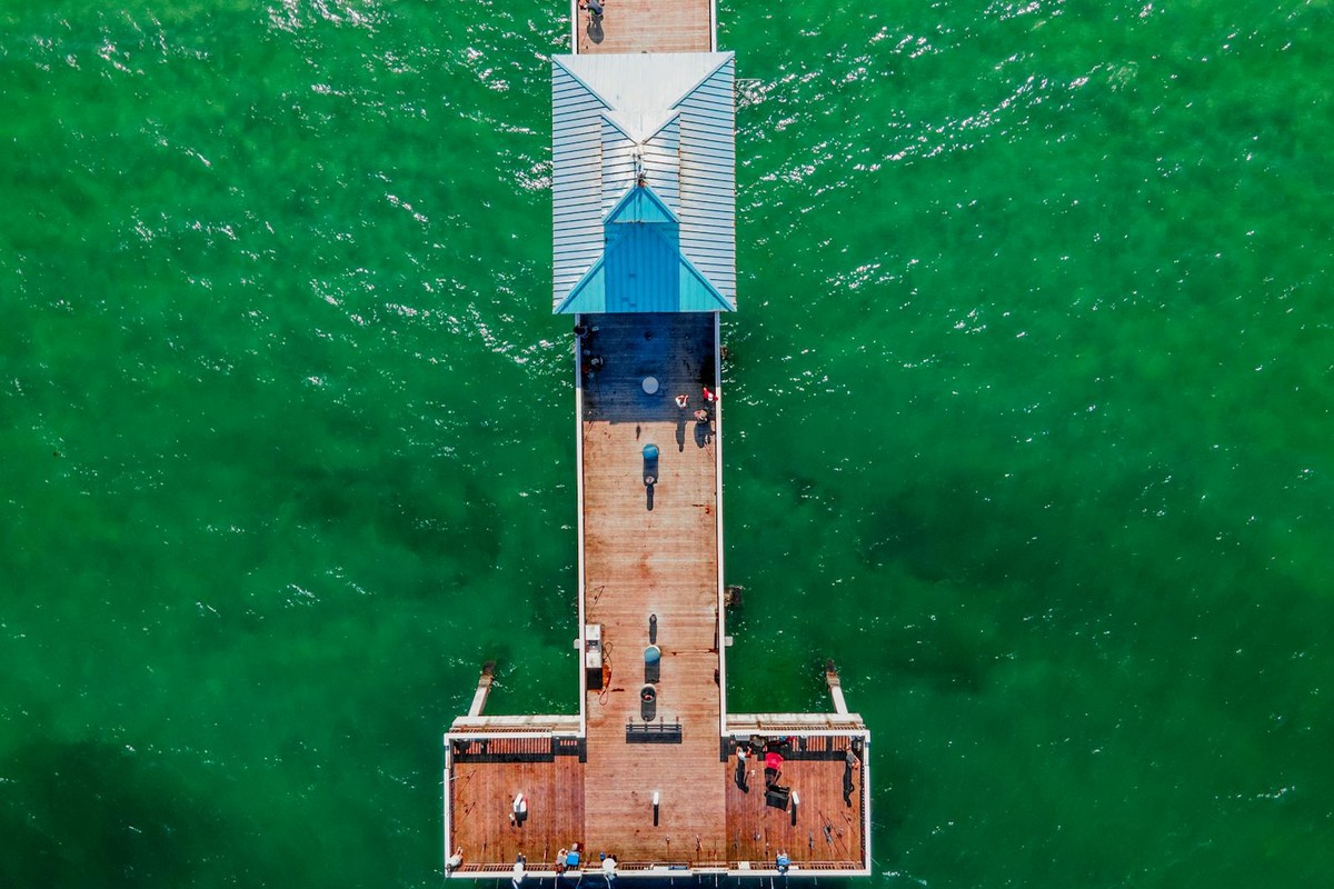 Stunning aerial view of Deerfield Beach Pier, showcasing vibrant green waters and a sunny day.