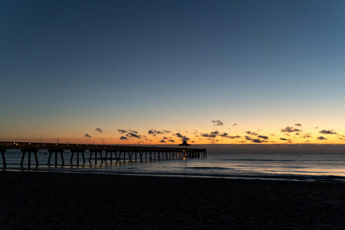Peaceful sunset view of a silhouette pier stretching into the calm ocean waters.