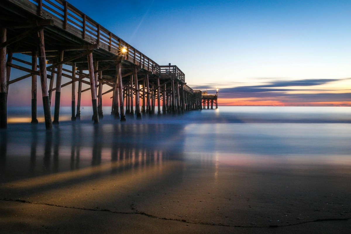 A tranquil evening at Tustin Pier with stunning sunset reflections on the ocean.