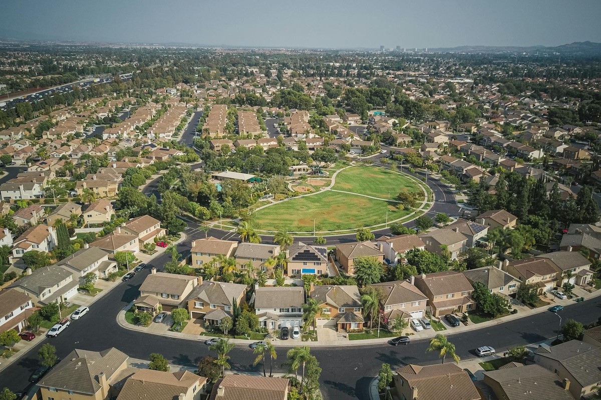 Drone aerial view of a spacious suburban neighborhood with a central park area.
