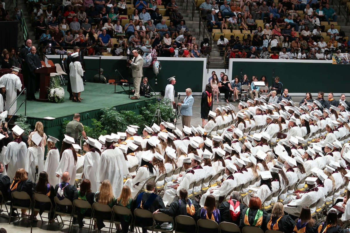 A large graduation ceremony with students in caps and gowns gathered indoors at Hammond, LA.