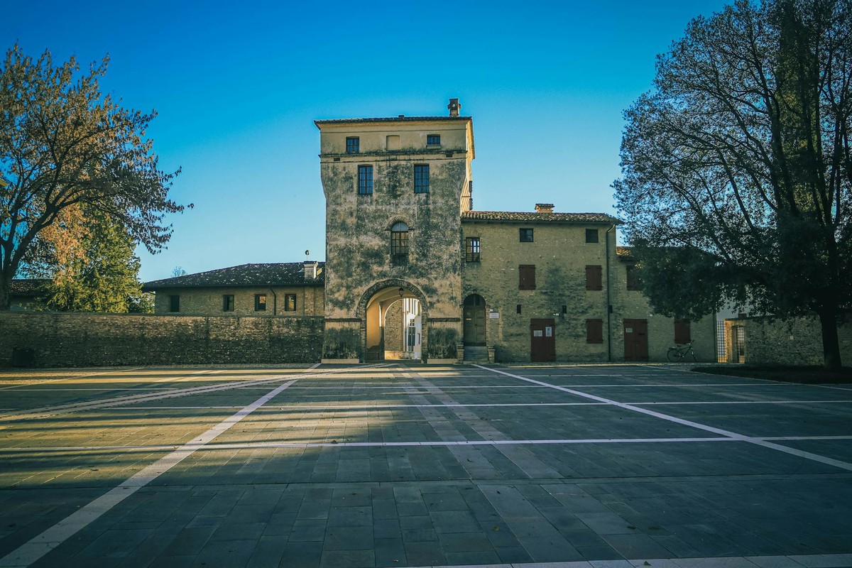 A historic stone building with an arched gateway lit by sunlight, showcasing architectural beauty.