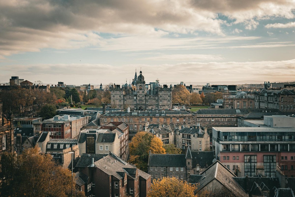 Stunning panoramic view of Edinburgh cityscape with autumn foliage and historic architecture.