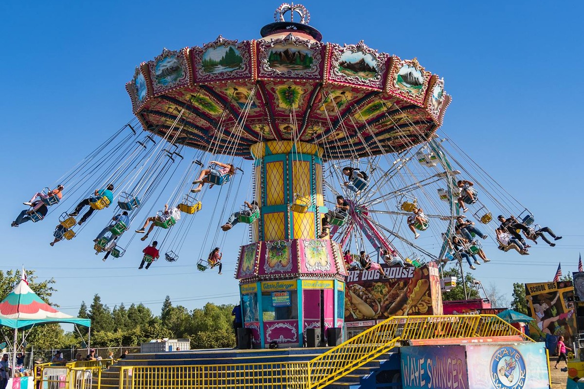 Vibrant carousel ride at Merced County Fair in California on a sunny day, showcasing joyful amusement park fun.
